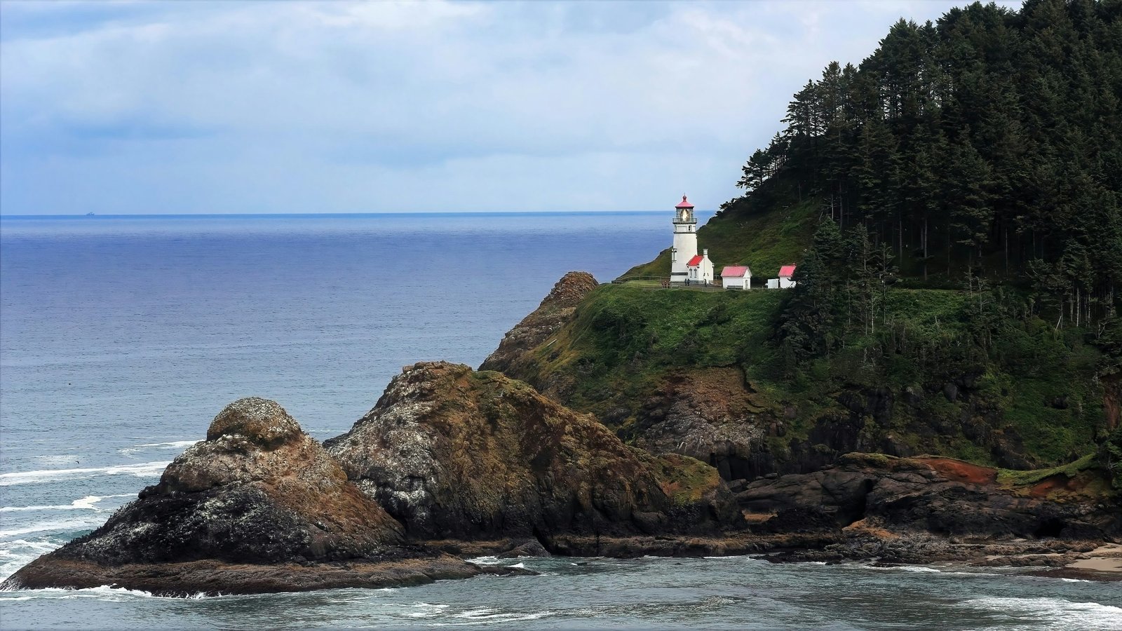 white and red lighthouse on brown rock formation near body of water during daytime